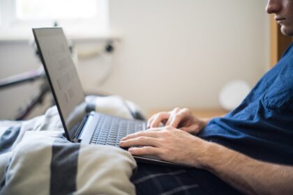 Sawir kayd ah: Working from Bed - A Man Works from Home with a Laptop in Bed
